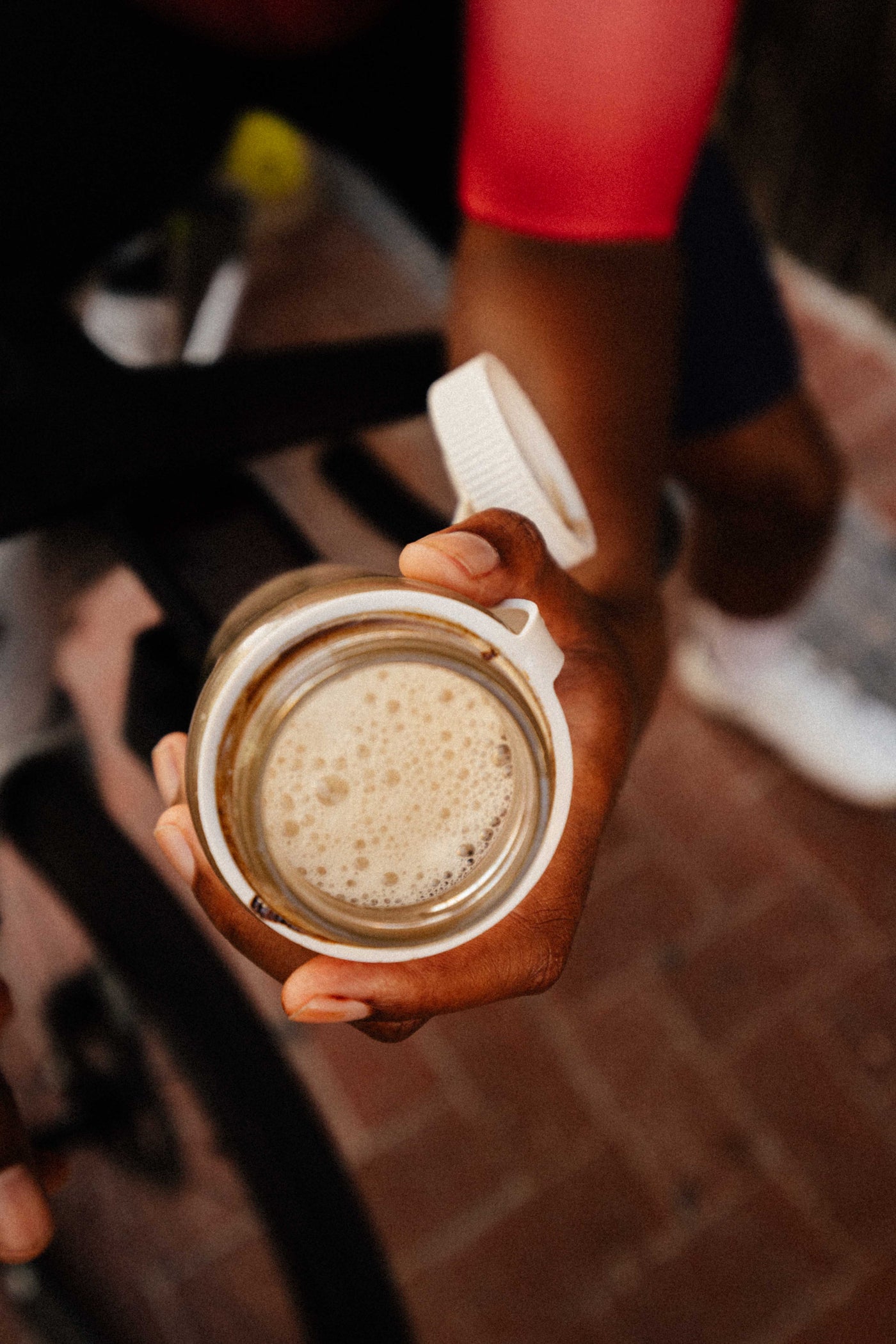 Hand holding a mason jar with a creamy beverage on a blurred street background