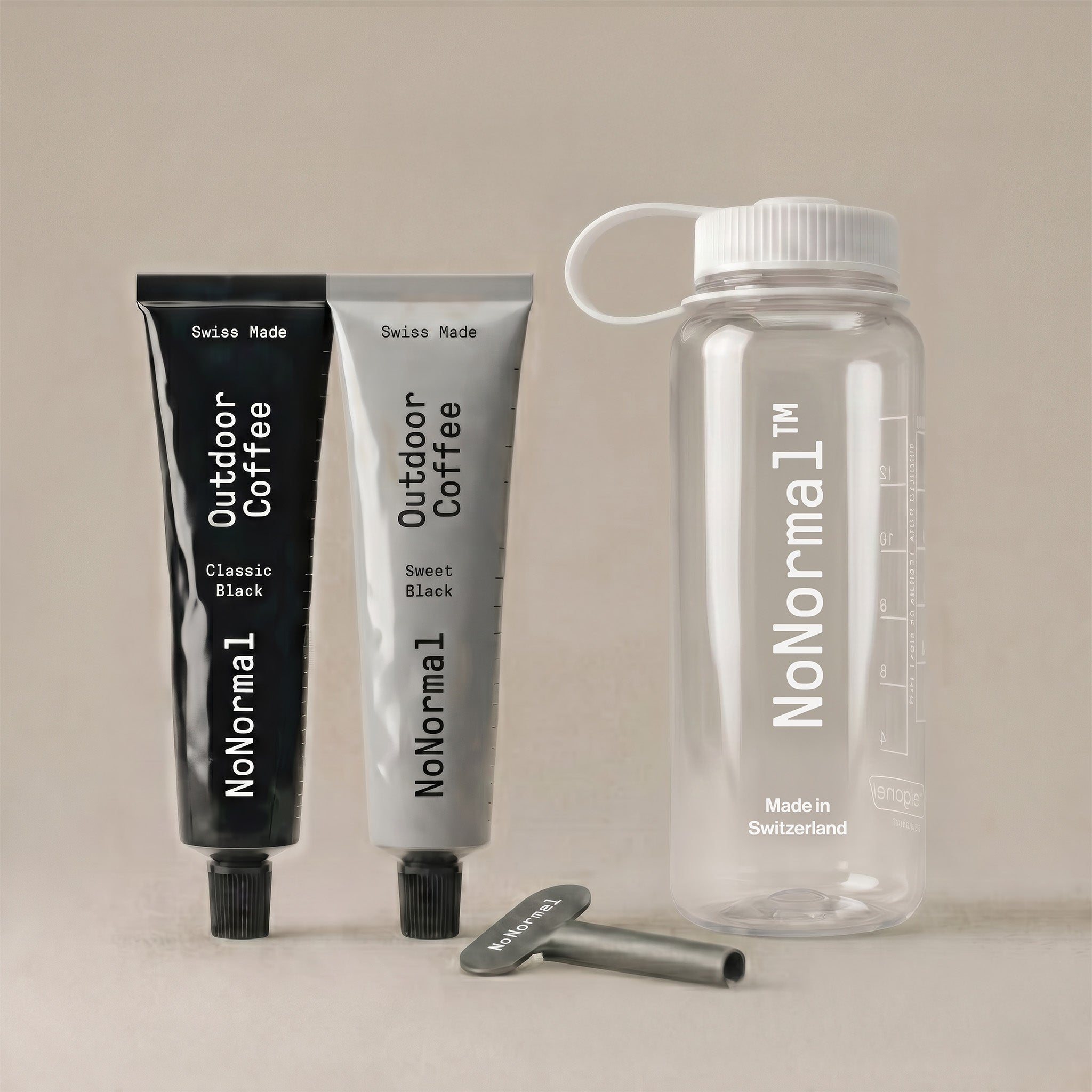 A NoNormal travel set featuring a clear water bottle with a white cap and loop, two tubes of coffee