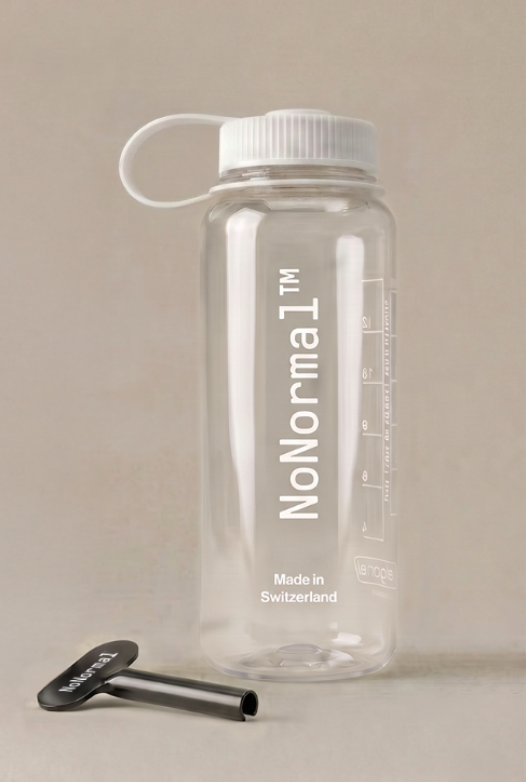 A clear plastic water bottle with a white screw cap and carrying loop, labeled 'NoNormal' in white text, shown on a warm beige background with a small black accessory in front.