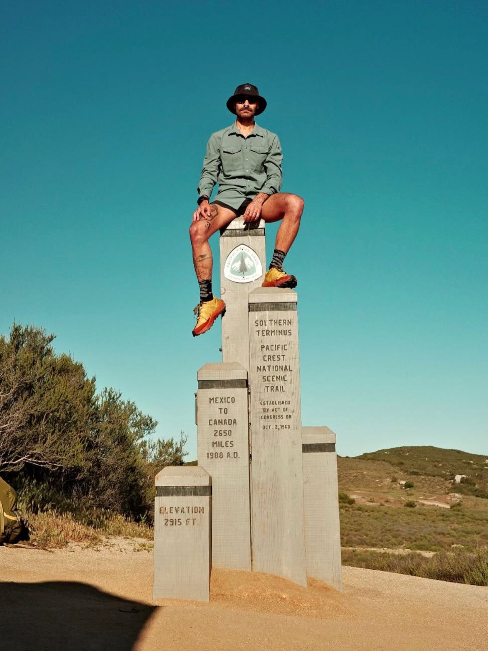 Person sitting on a monument with a clear blue sky and desert landscape